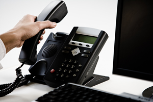 Person Next to a Computer Picking Up a Phone